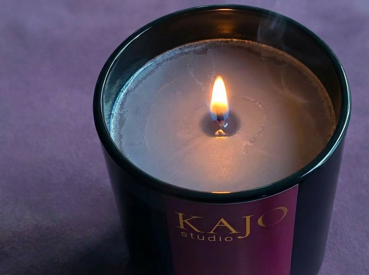 Candle in a black container with 'Kajo Studio' branding on a purple background